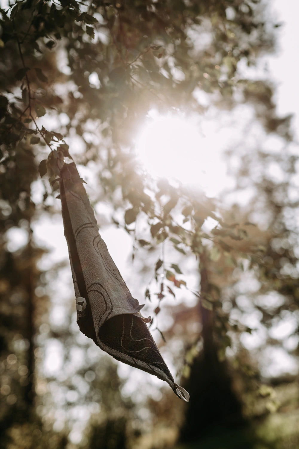 Pellavainen musta-beige retkipyyhe kuivuu puun oksalla